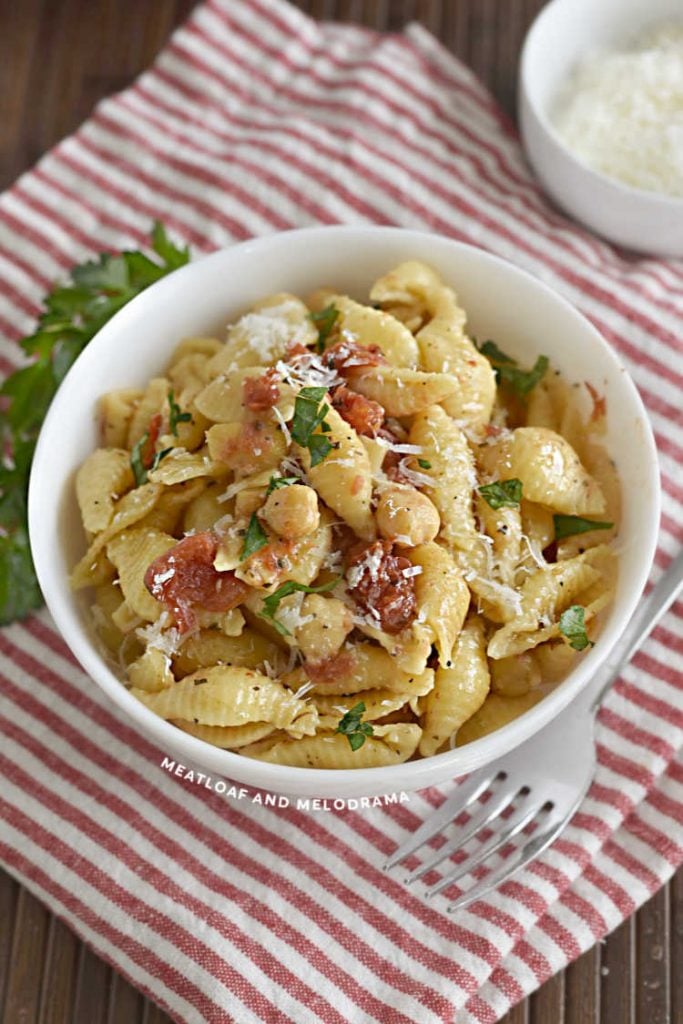 bowl of shell pasta with chickpeas and diced tomatoes with parsley and parmesan