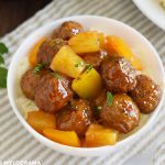 sweet and sour meatballs with pineapple and yellow bell peppers in a white bowl