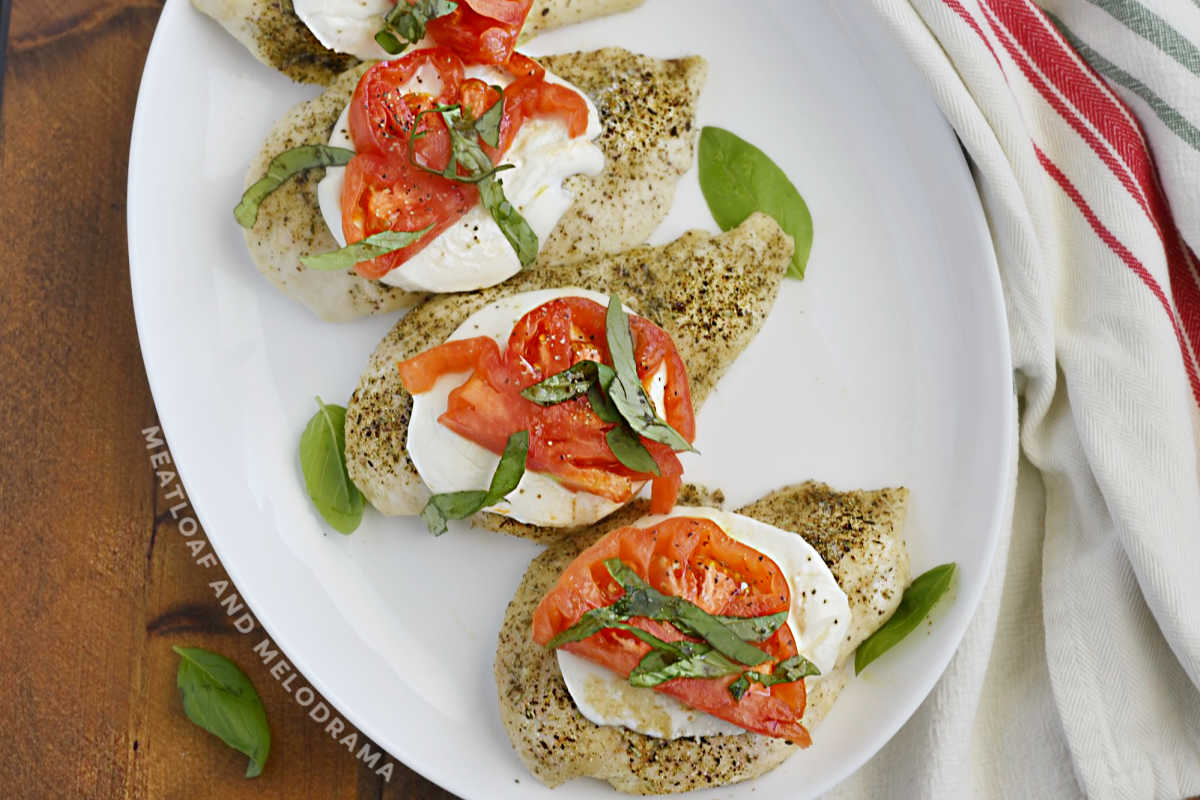 caprese chicken with mozzarella, tomato slices and basil leaves on a platter