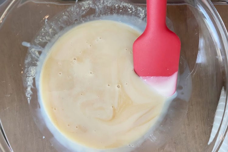 red spatula stirring condensed milk and vanilla in mixing bowl