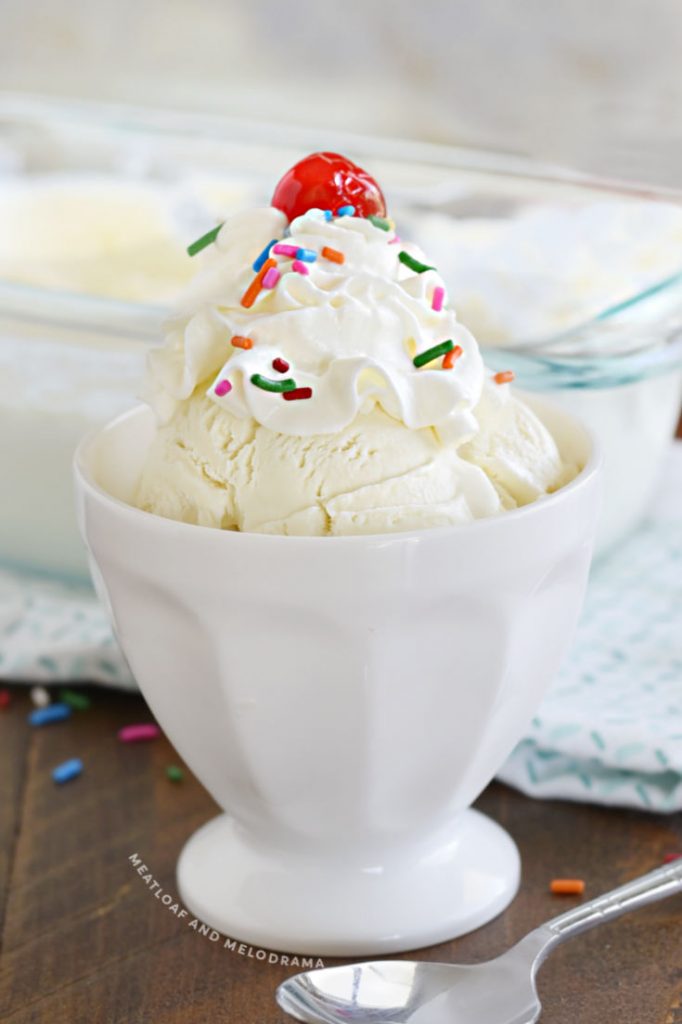 no churn vanilla ice cream in a white sundae bowl with whipped cream and sprinkles