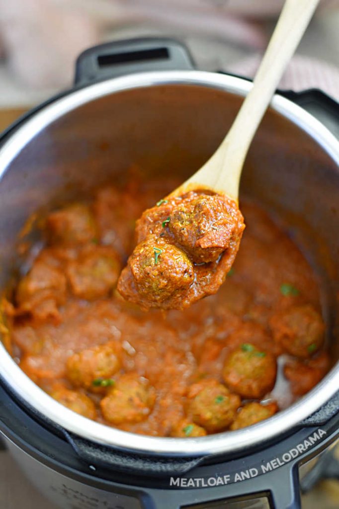 meatballs on a wooden spoon over the pressure cooker
