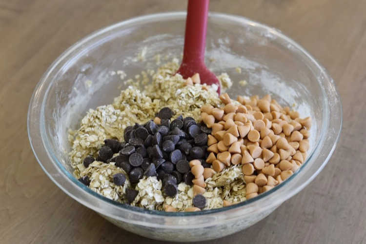 cookie dough with oats, chocolate chips and butterscotch chips in a mixing bowl