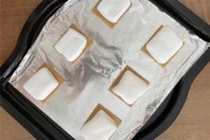 graham cracker halves with marshmallows on top on baking sheet