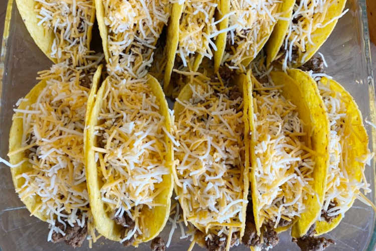 shredded cheese over beef in  taco shells