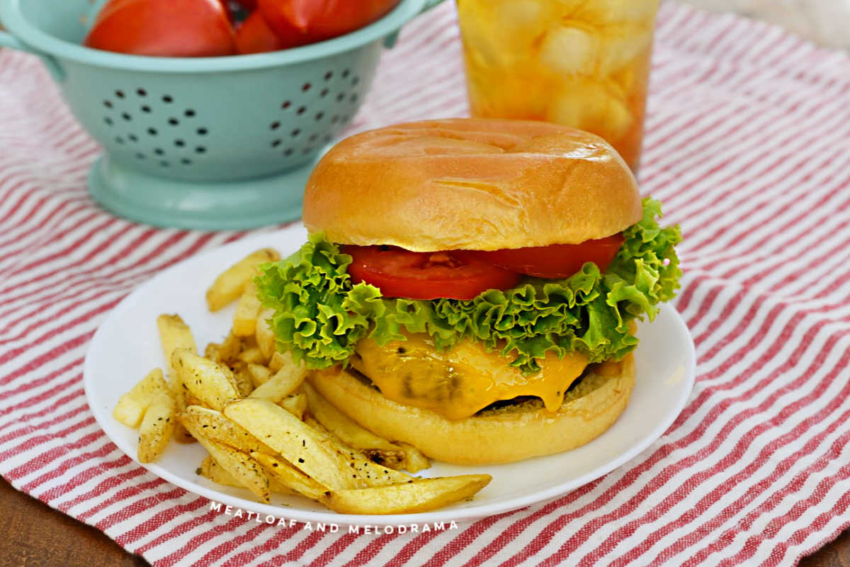 air fryer hamburger with melted cheese, lettuce and tomato slices on a plate with fries