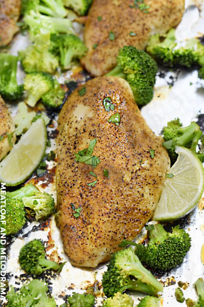 baked chicken with broccoli and lime wedges on sheet pan