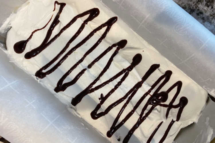 chocolate syrup drizzled over whipped topping on ice cream cake