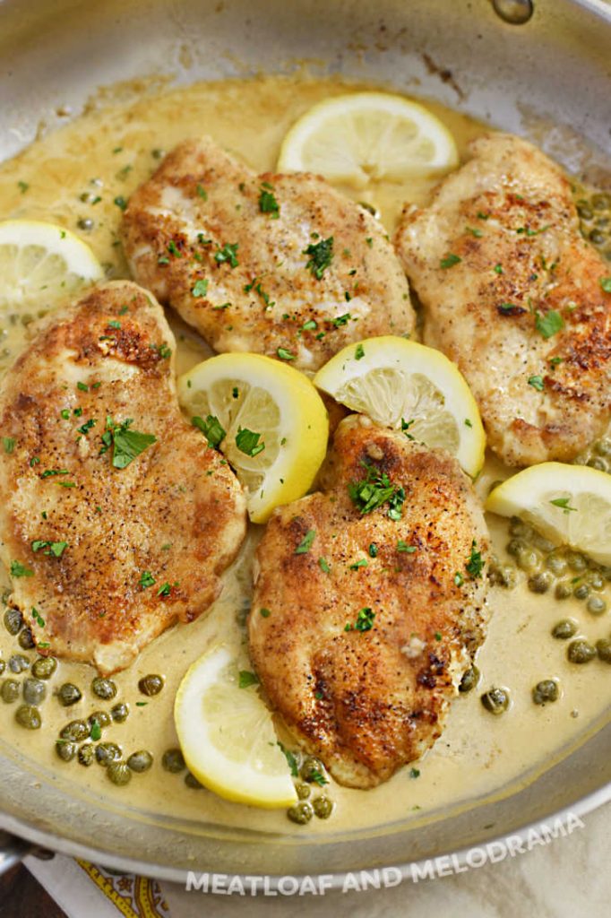 pan fried lemon chicken breasts in lemon cream sauce with capers in skillet