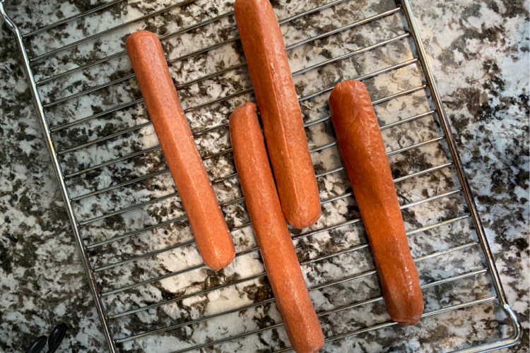 uncooked hot dogs on an air fryer oven rack
