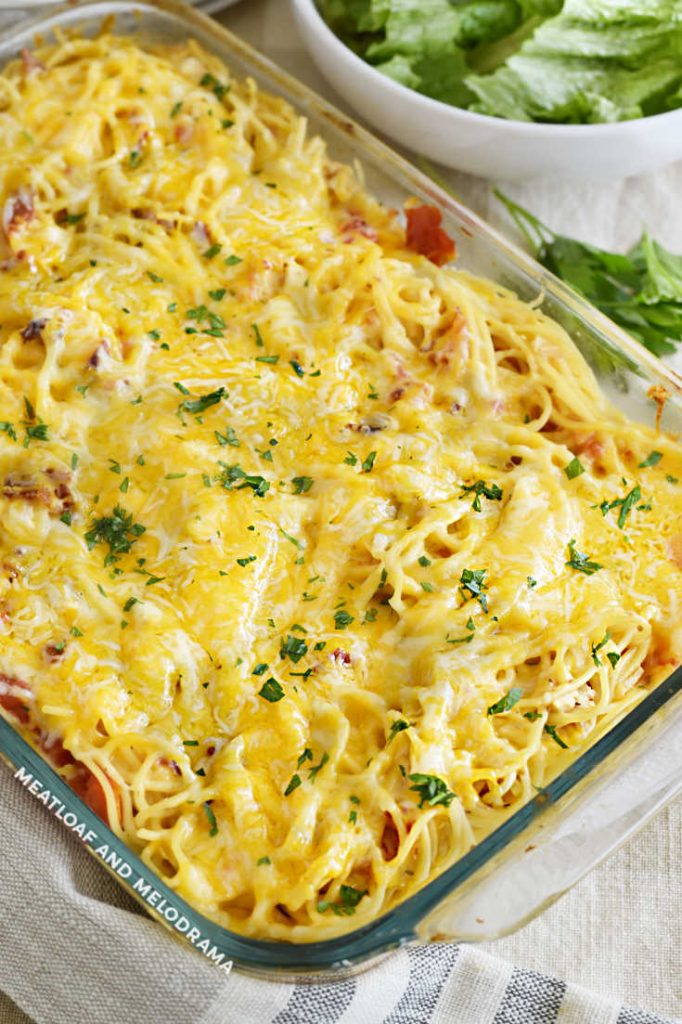 baked cheesy chicken pasta in casserole dish with salad bowl