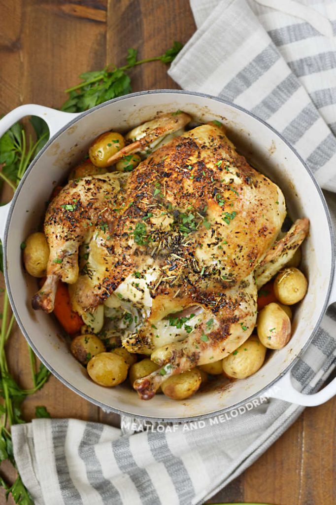 whole cooked chicken in dutch oven with potatoes and carrots