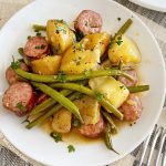 kielbasa sausage with baby potatoes and green beans on a white plate