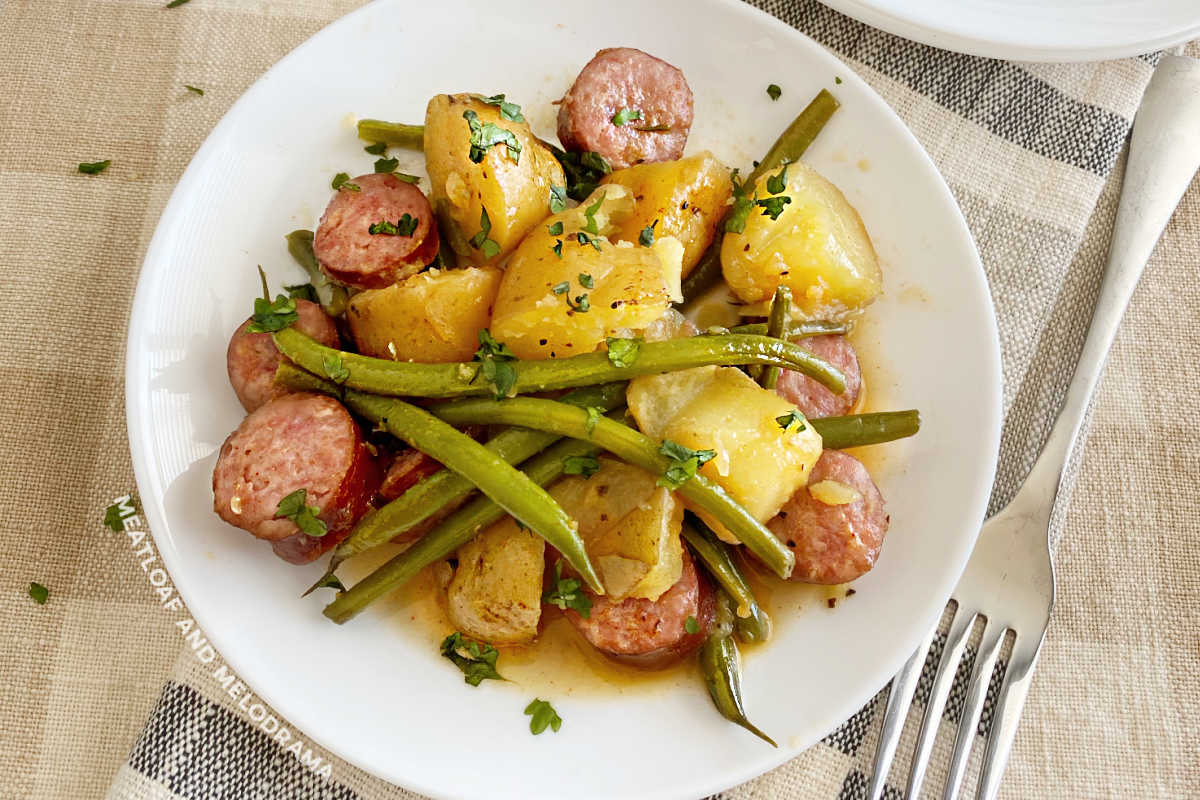 kielbasa sausage with baby potatoes and green beans on a white plate