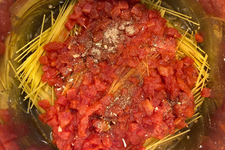 diced tomatoes over spaghetti noodles in pressure cooker