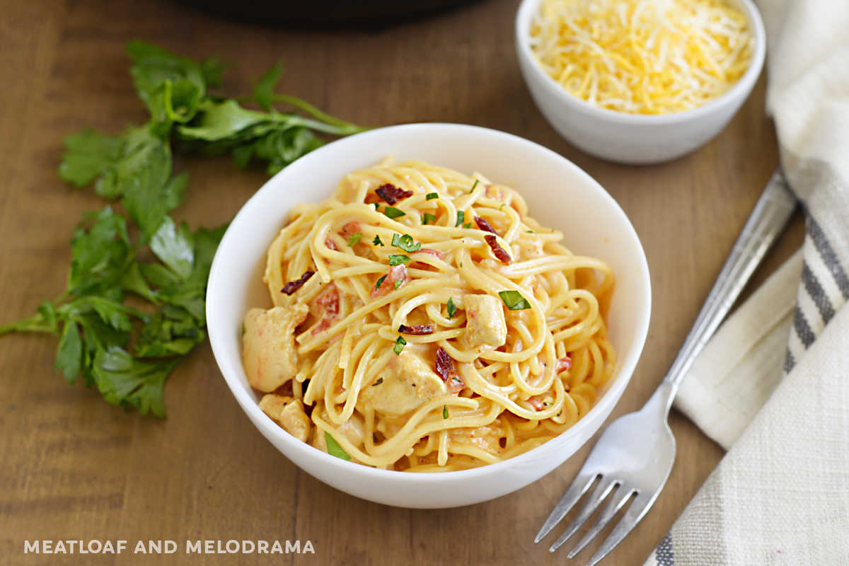 bowl of instant pot chicken spaghetti with bacon and parsley and cheese on the table