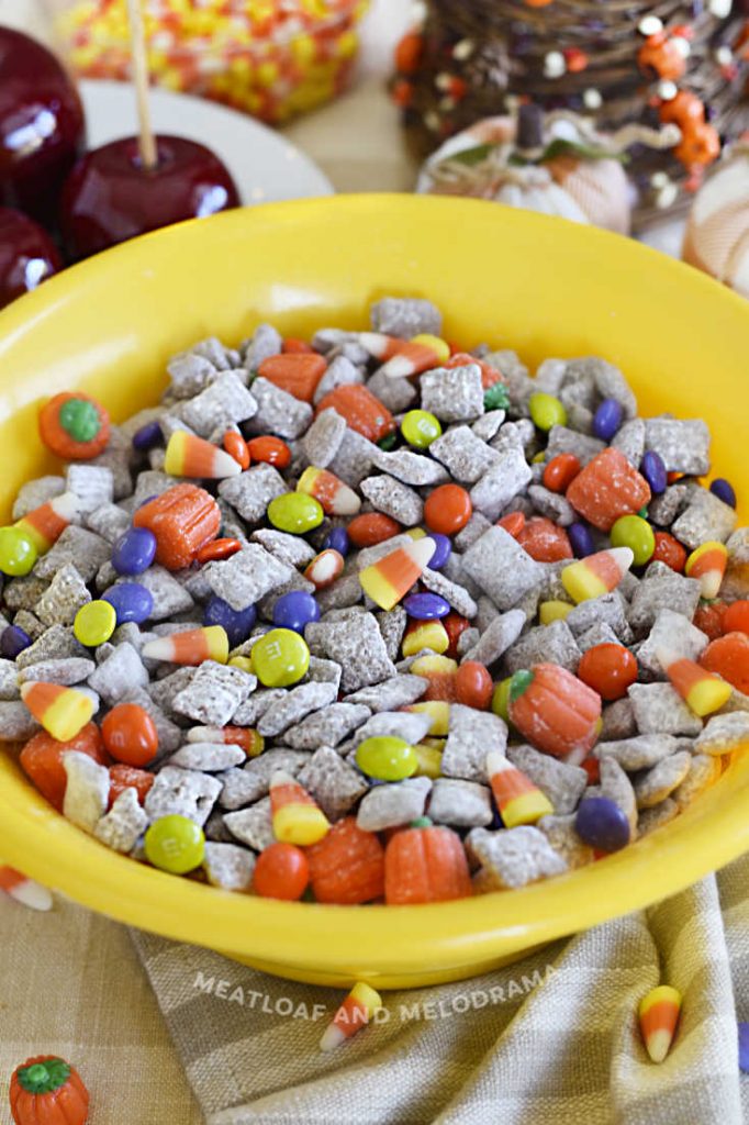 fall puppy chow muddy buddies in a yellow bowl with halloween candy