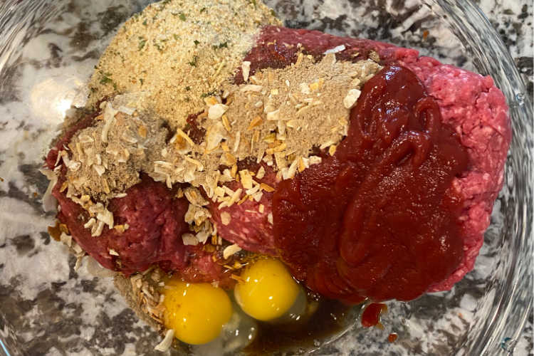 ground beef and ingredients for onion soup meatloaf in glass mixing bowl