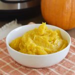 bowl of cooked pumpkin puree with instant pot pressure cooker and whole sugar pumpkin in background