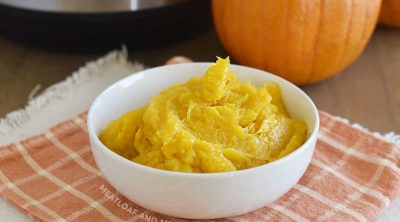 bowl of cooked pumpkin puree with instant pot pressure cooker and whole sugar pumpkin in background