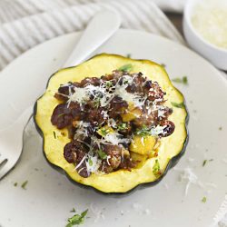 sausage stuffed acorn squash with apples and cranberries on a plate