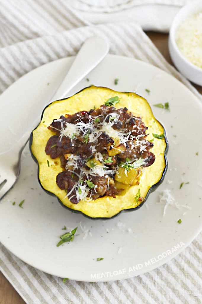 baked acorn squash with Italian sausage, apples and cranberries on a white plate