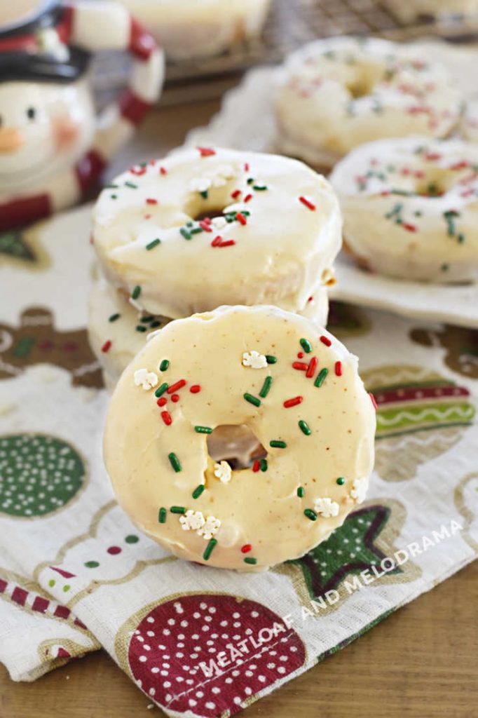 eggnog donuts topped with eggnog glaze and red and green sprinkles on table