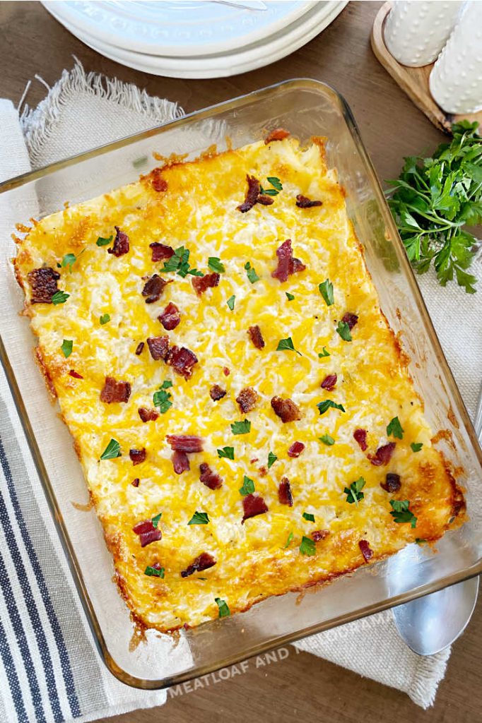 overhead photo of hash brown potato bake with cheese and bacon in a glass baking dish
