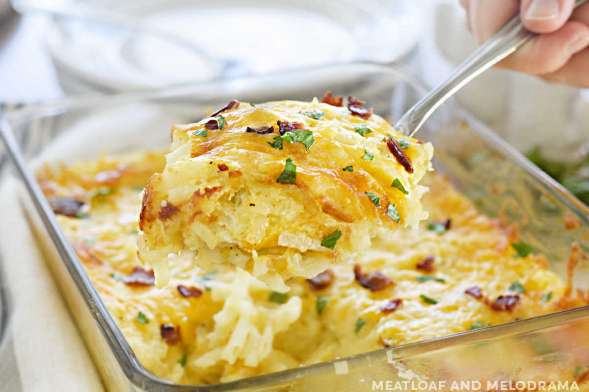 cheesy hashbrown potato casserole on a serving spoon with bacon