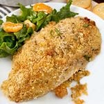 ritz cracker baked chicken breast on a white plate with salad