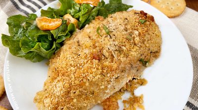 ritz cracker baked chicken breast on a white plate with salad