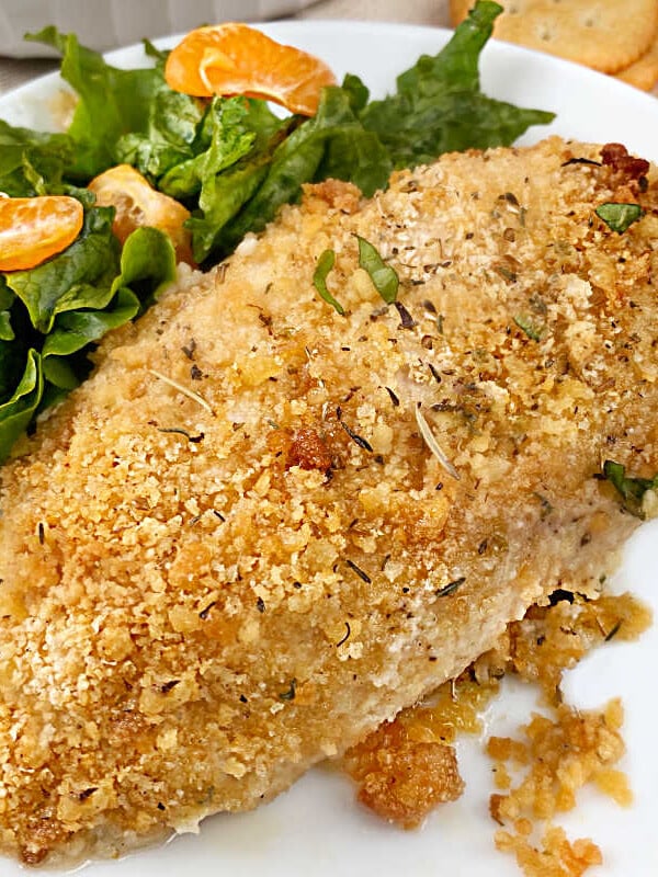 ritz cracker baked chicken breast on a white plate with salad