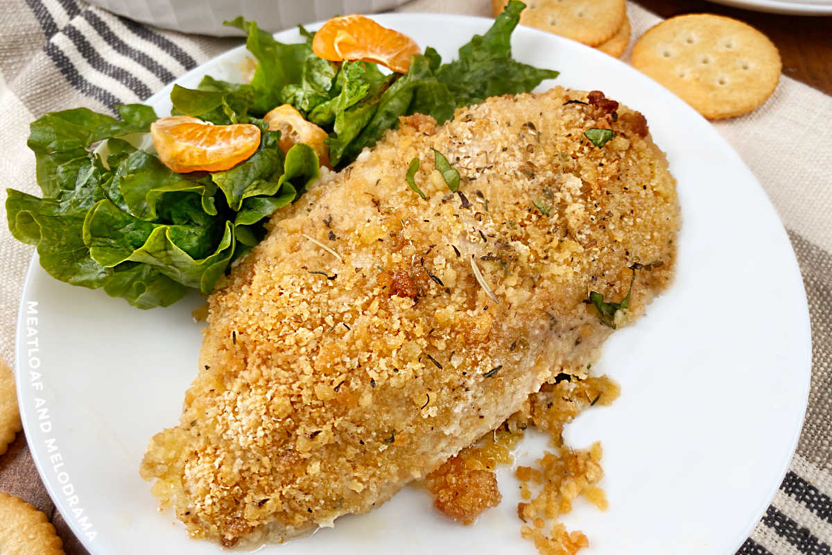 ritz cracker baked chicken breast on a white plate with salad