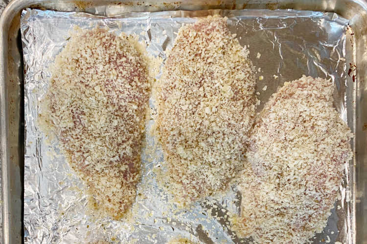 parmesan panko coated chicken breasts on baking sheet