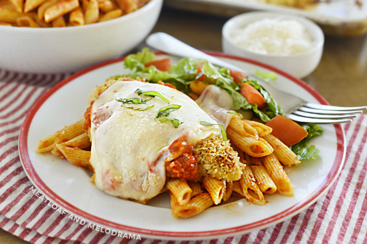baked chicken parmesan over penne on a plate