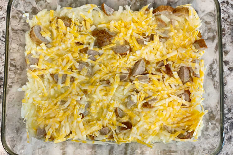 hash brown potatoes, sausage slices and shredded cheese in a casserole dish
