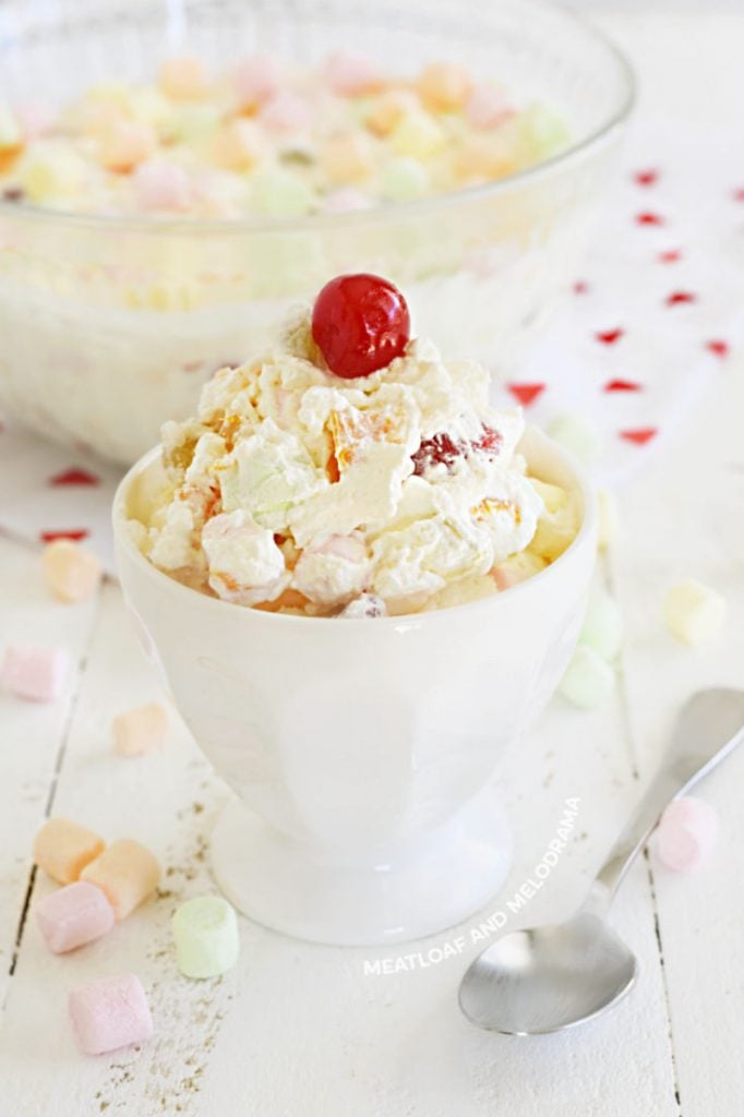 cocktail de fruta com chicote fresco e marshmallows em prato branco com cereja em cima