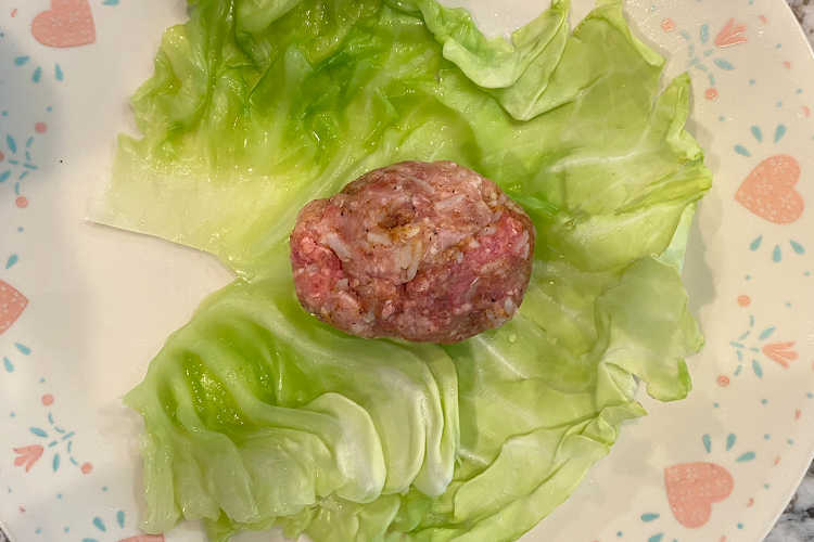 meat and rice mixture on a cabbage leaf