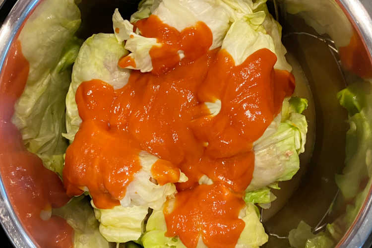 uncooked cabbage rolls topped with tomato soup in the instant pot pressure cooker