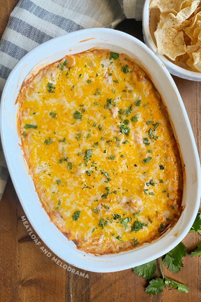 hot bean dip with melted cheese and cilantro in white casserole dish