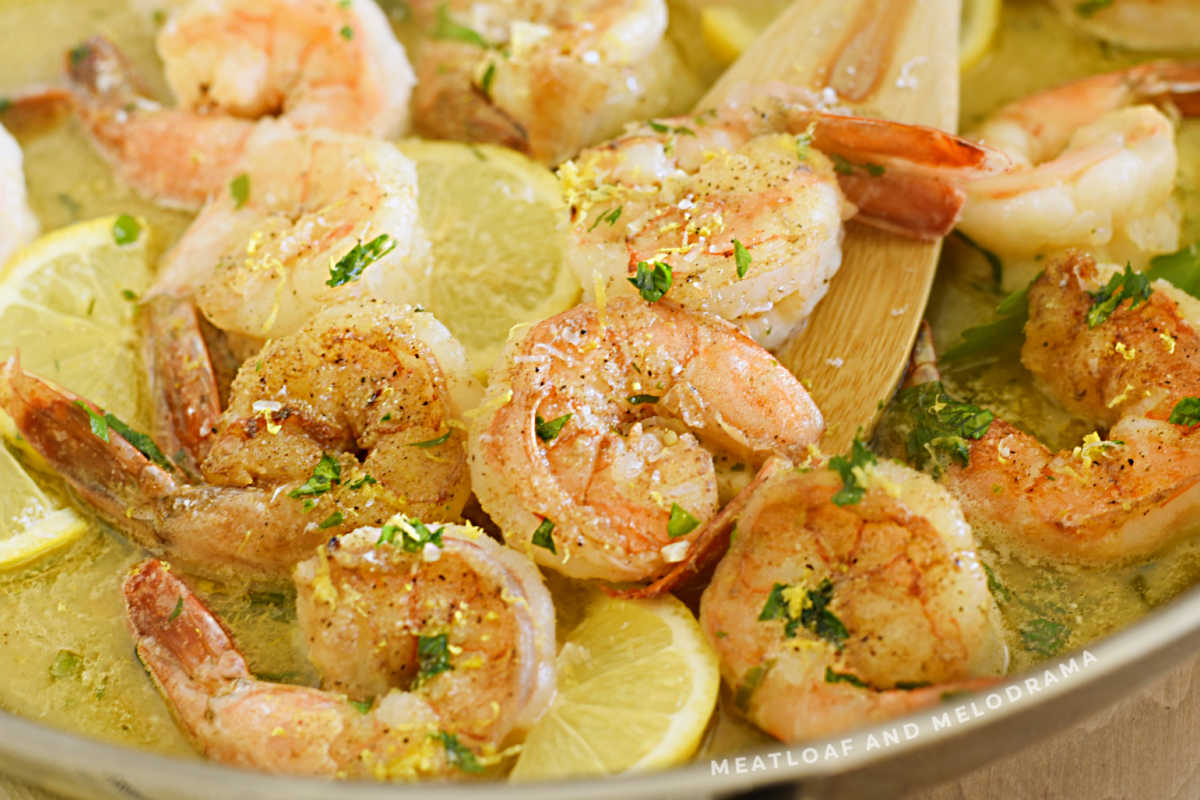 shrimp scampi in a pan with lemons and parsley