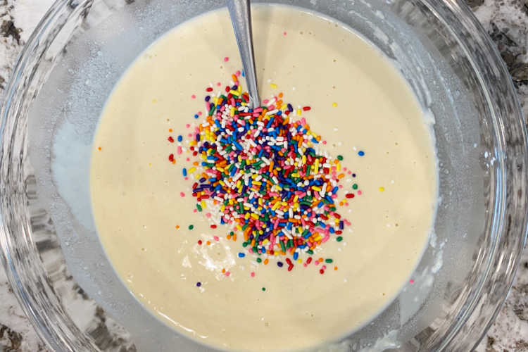 waffle batter in a mixing bowl with rainbow colored sprinkles