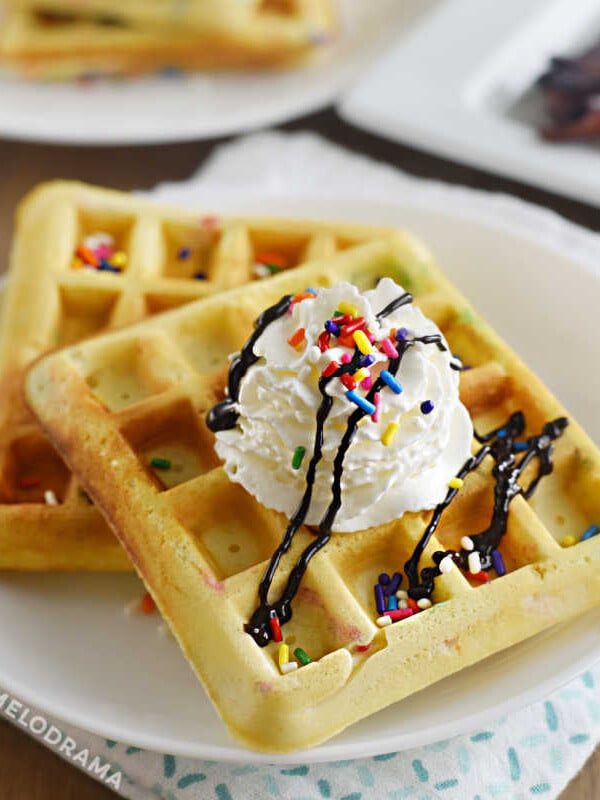 2 funfetti waffles with sprinkles and whipped cream on a plate