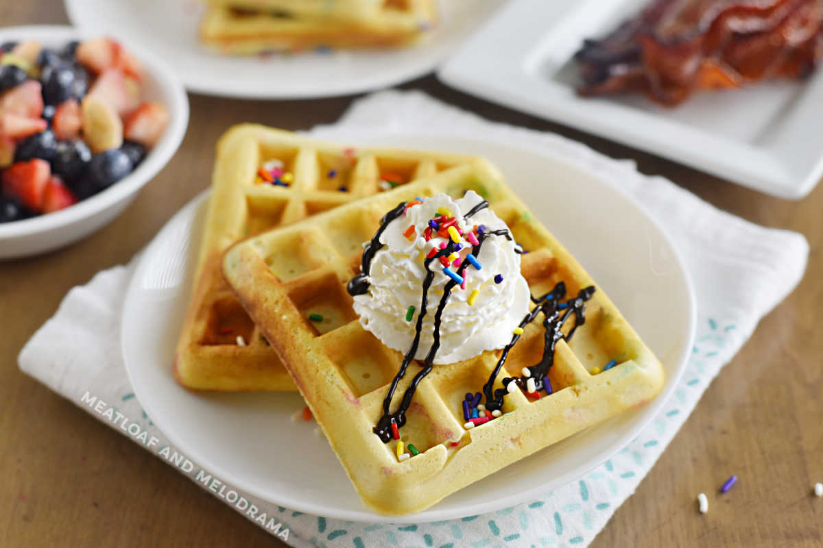 2 funfetti waffles with candy sprinkles and whipped cream on a plate