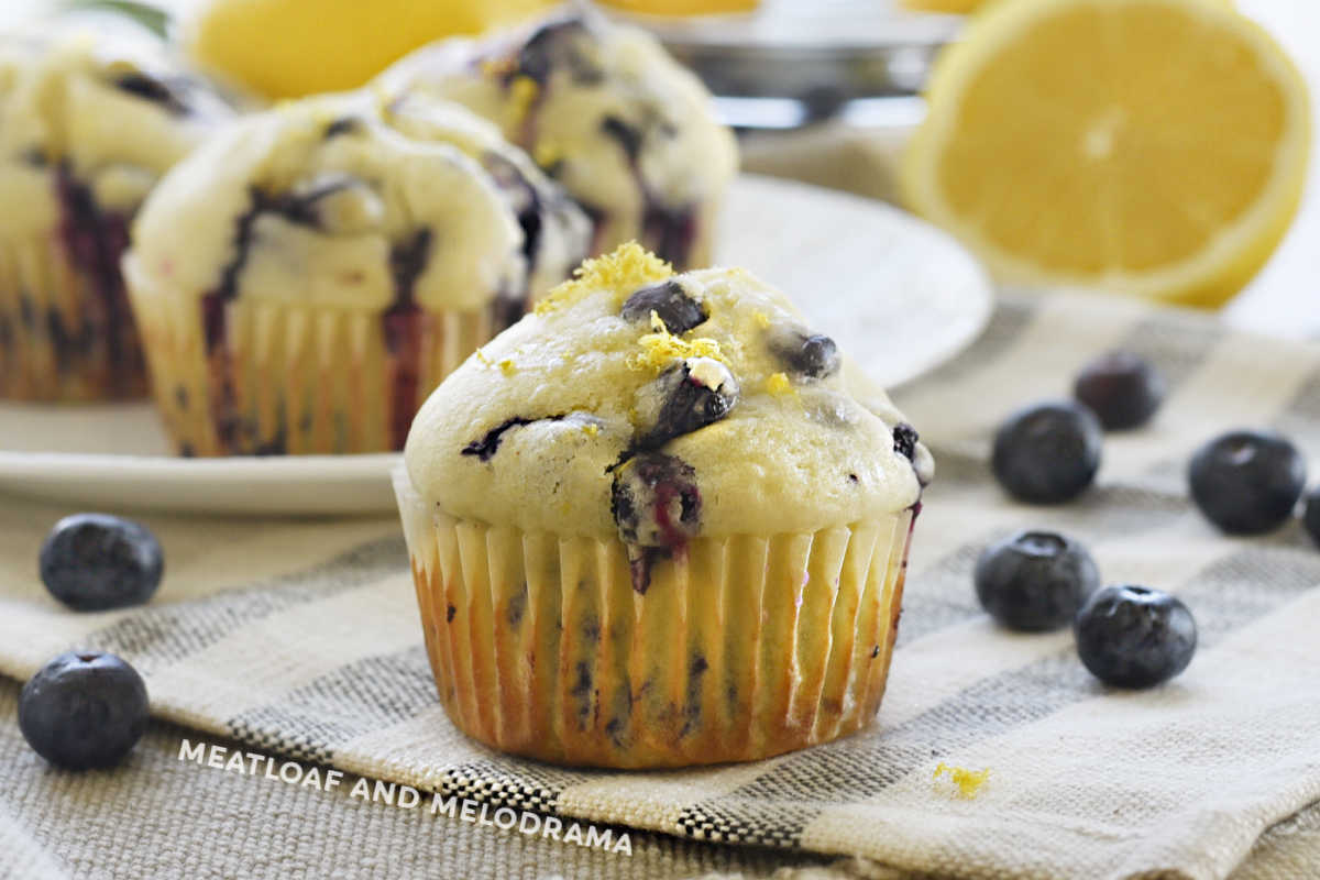 lemon blueberry muffin with glaze and lemon zest on the table with fresh blueberries