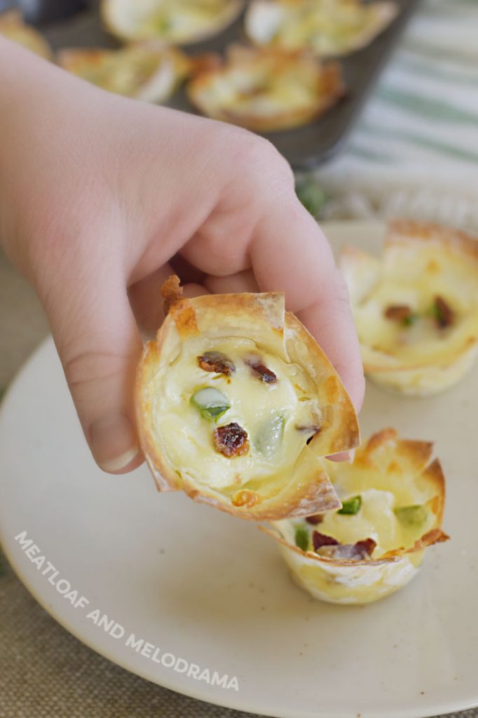 hand holding mini wonton cups with jalapeño peppers and bacon