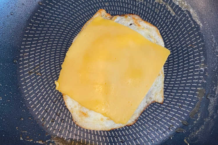 fried egg with a slice of American cheese in a pan