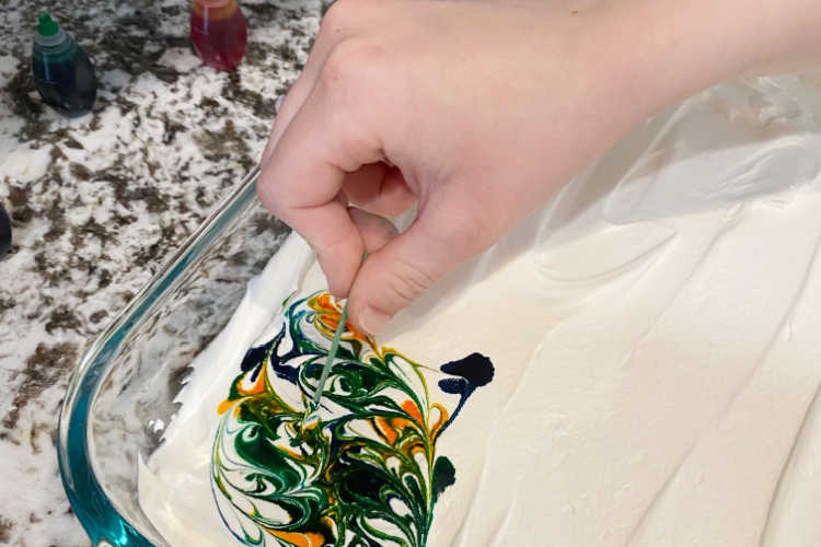 swirl food coloring in whipped topping with toothpick
