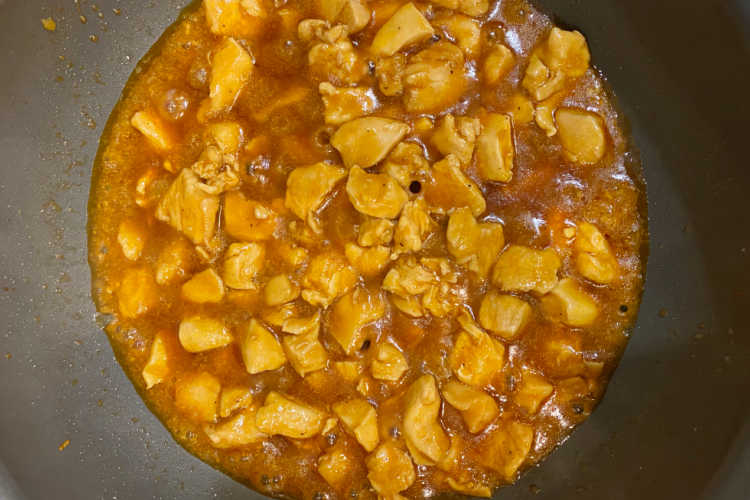 cubed chicken simmering in bourbon sauce