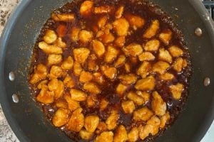cubed chicken breasts in orange sauce in wok